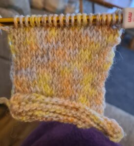 Pink yellow and blue coloured yarn on a Tunisian Crochet hook