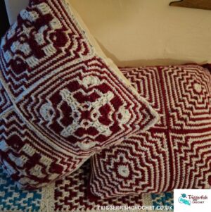 Red and white crochet cushion covers in mosaic pattern granny squares joined together, over a red, turquoise and white mosaic mat